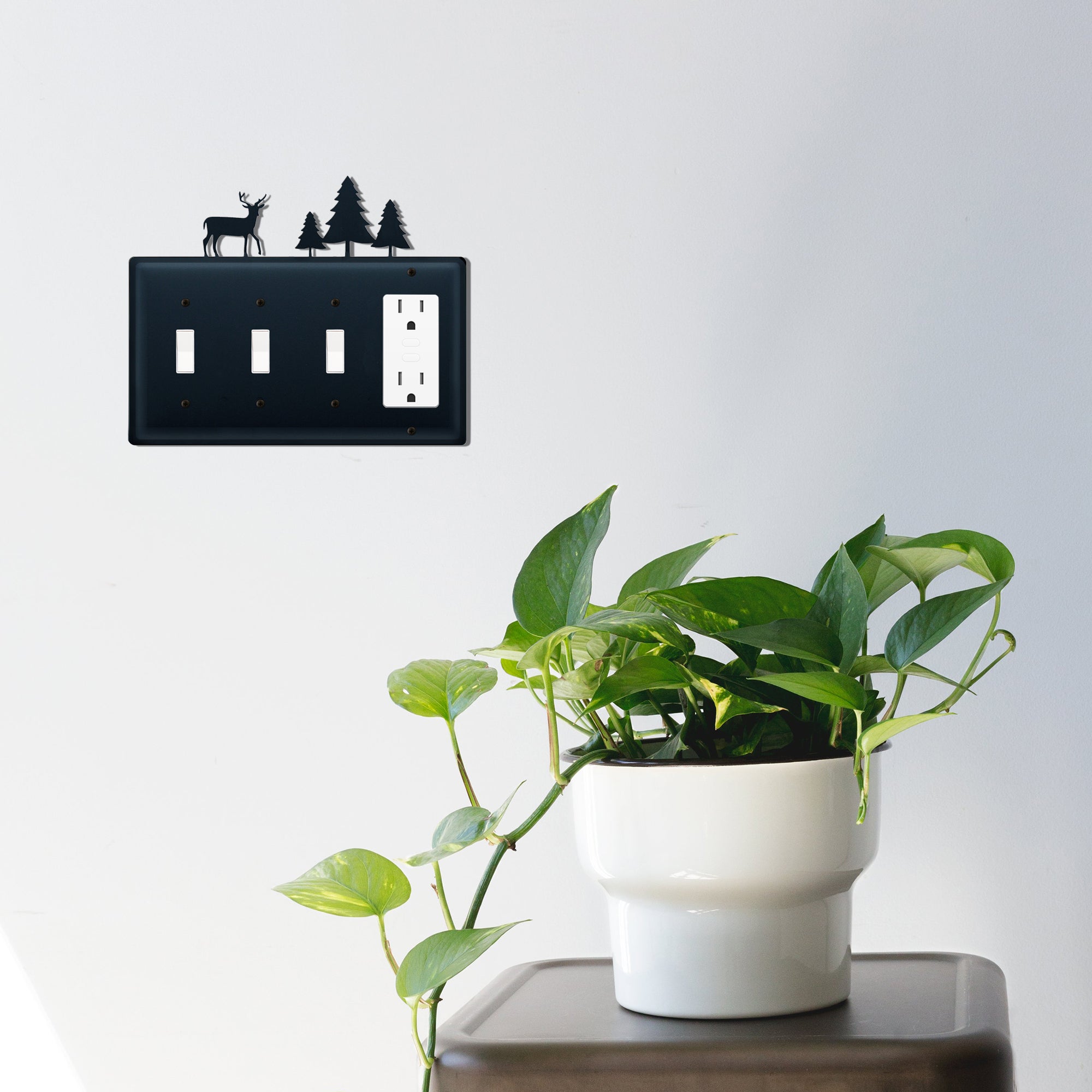 Deer and pine trees switch cover on wall with plant