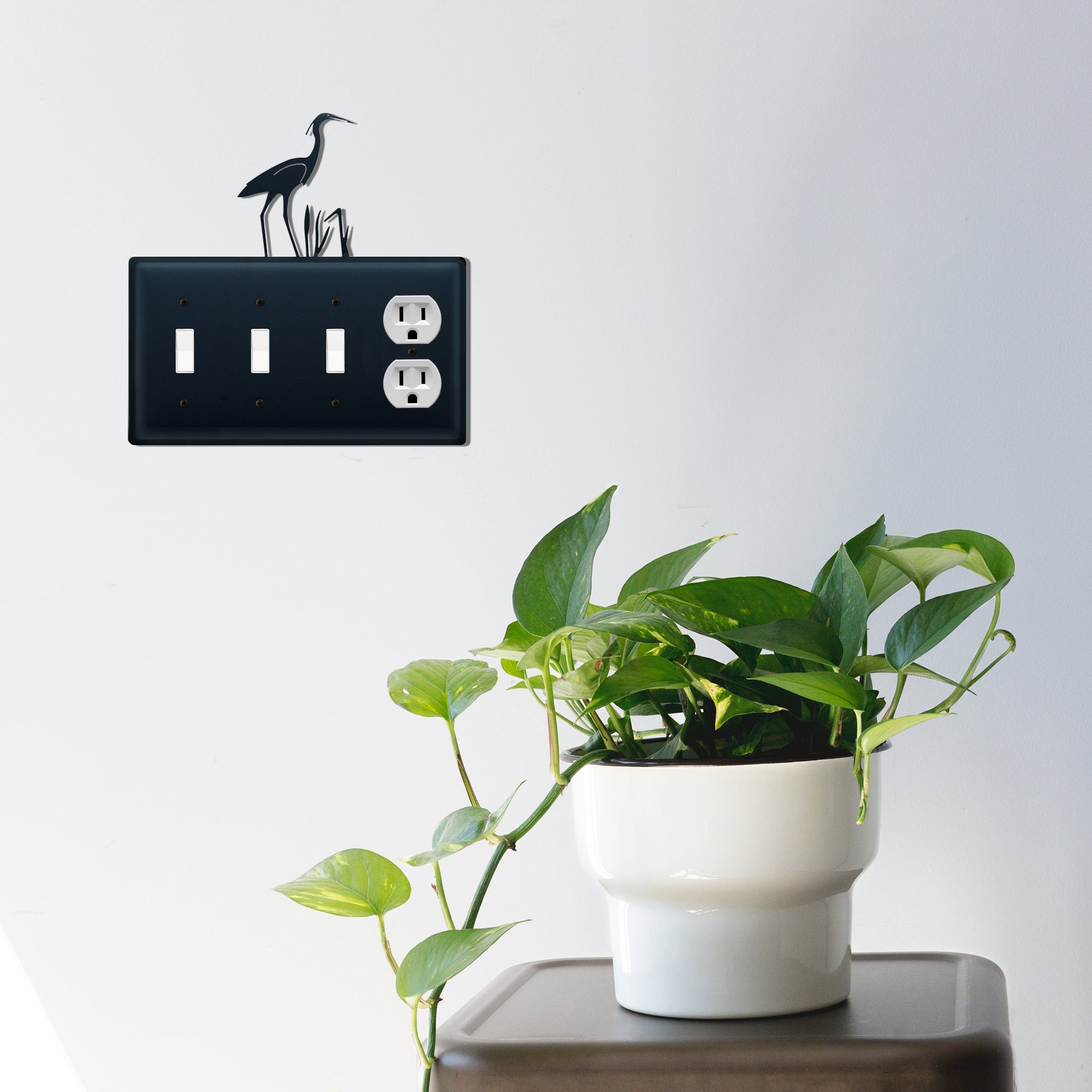 Heron design outlet cover on wall with plant decor